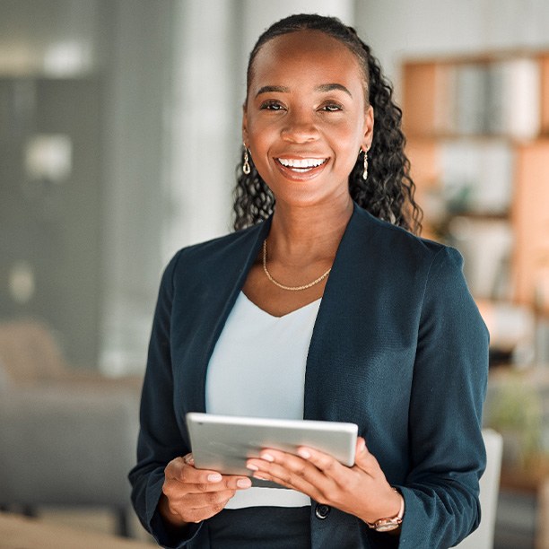 Woman smiling while holding tablet in office
