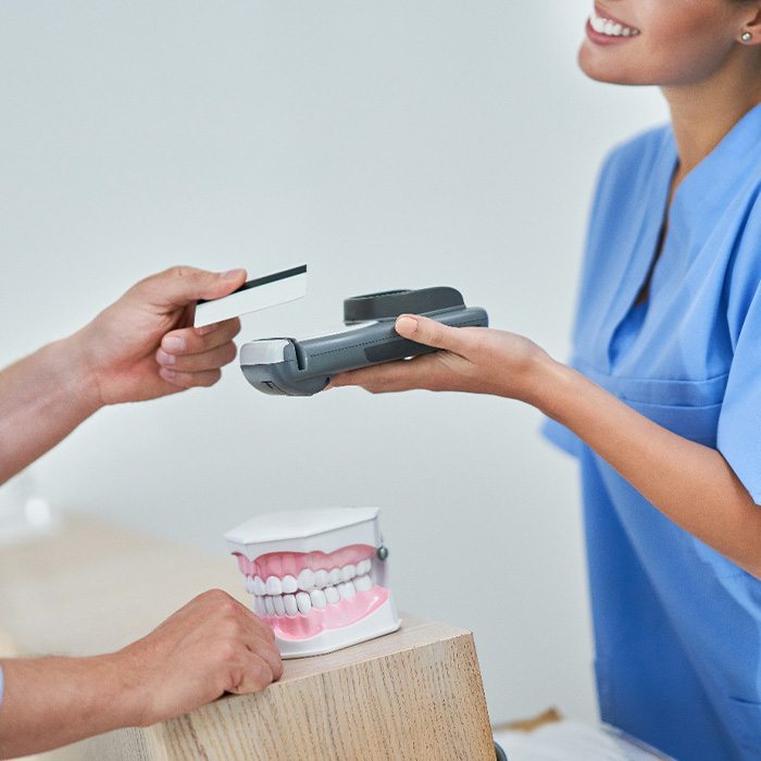 Smiling receptionist taking credit card payment from patient