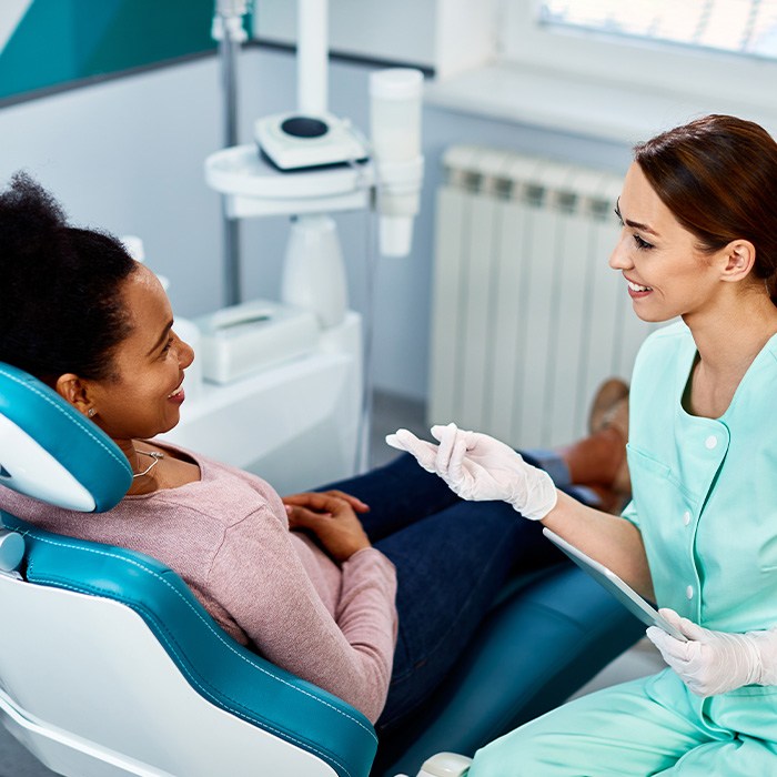 Smiling dentist talking to patient in exam room