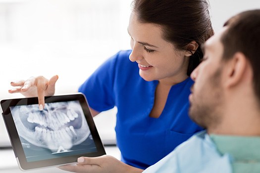 Smiling dentist reviewing X-ray with patient