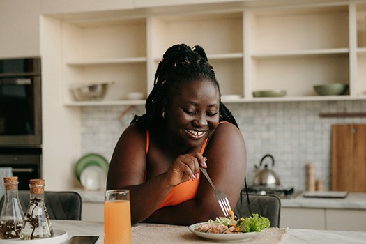 Woman smiling while eating lunch in kitchen at home