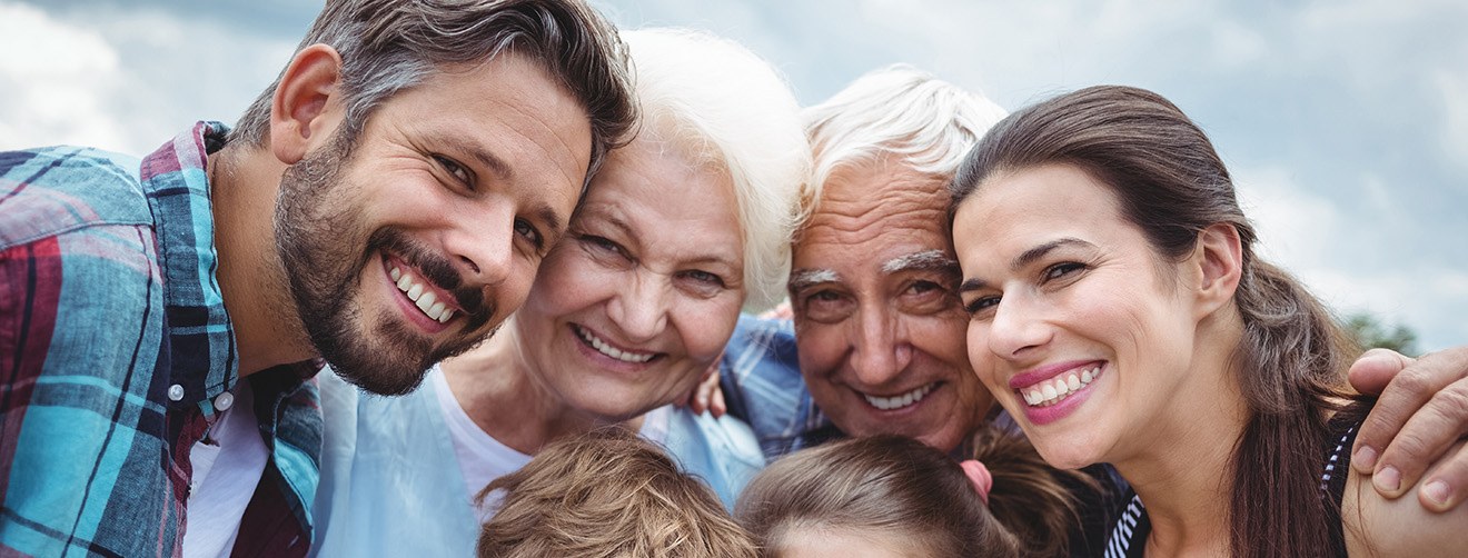 A smiling, multi-generation family standing outdoors