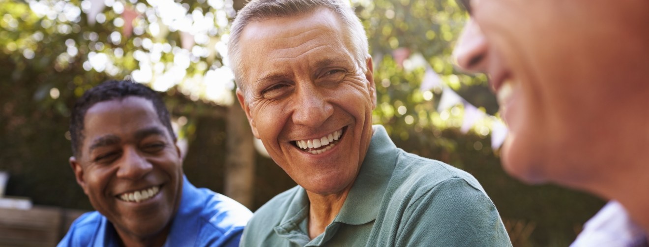 Three men laughing together outdoors after restorative dentistry in Athens