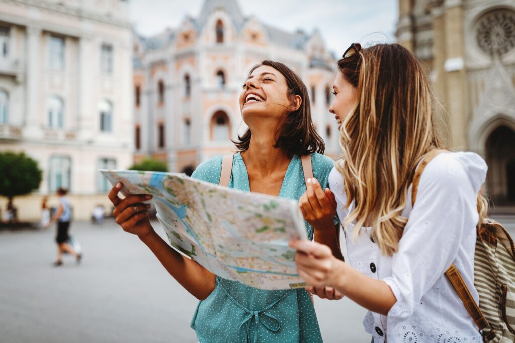 Two smiling female tourists looking at a map.